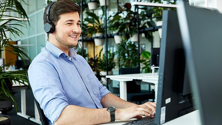 Mitarbeiter mit Headset am Schreibtisch im Büro